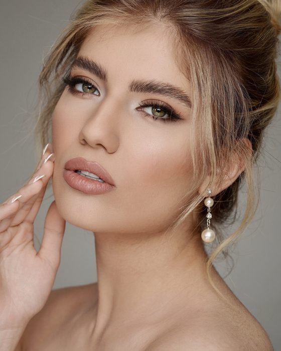 Moderner Nude-Bridal-Look mit weichen Brauntönen, gelifteter Augenform, dezenten Konturen und eleganten Perlenohrringen.